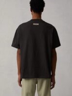Back view of a man in a black t-shirt and khaki pants, standing casually.