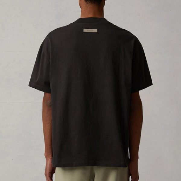 Back view of a man in a black t-shirt and khaki pants, standing casually.